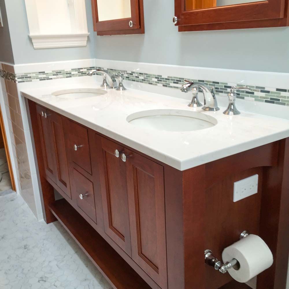 Bathroom vanity with double sinks, dark wood cabinets, white countertop, and mosaic tile backsplash.