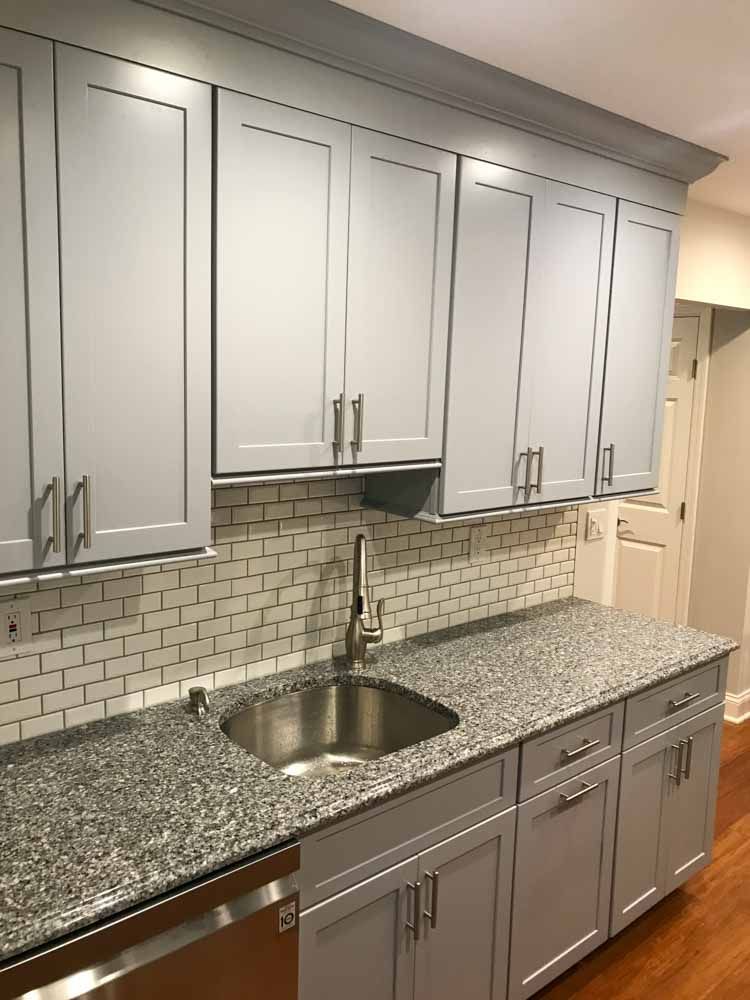 Kitchen with gray cabinets, granite countertops, stainless steel sink and appliances, white subway tile backsplash.