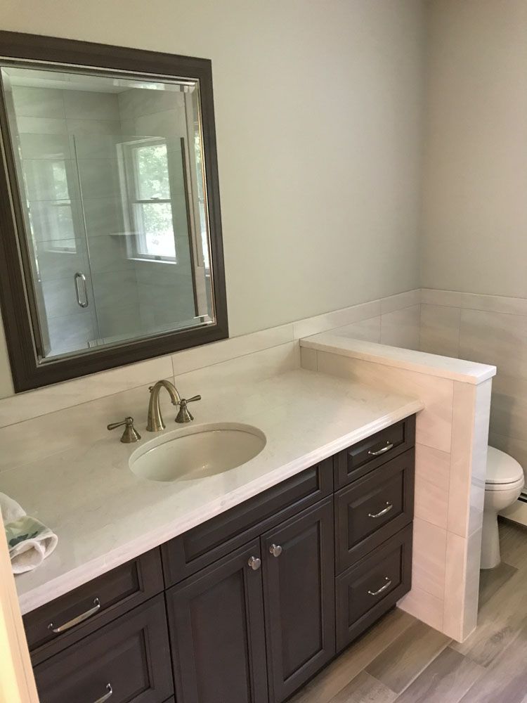 Bathroom with gray vanity, white countertop, oval sink, large mirror, and toilet.