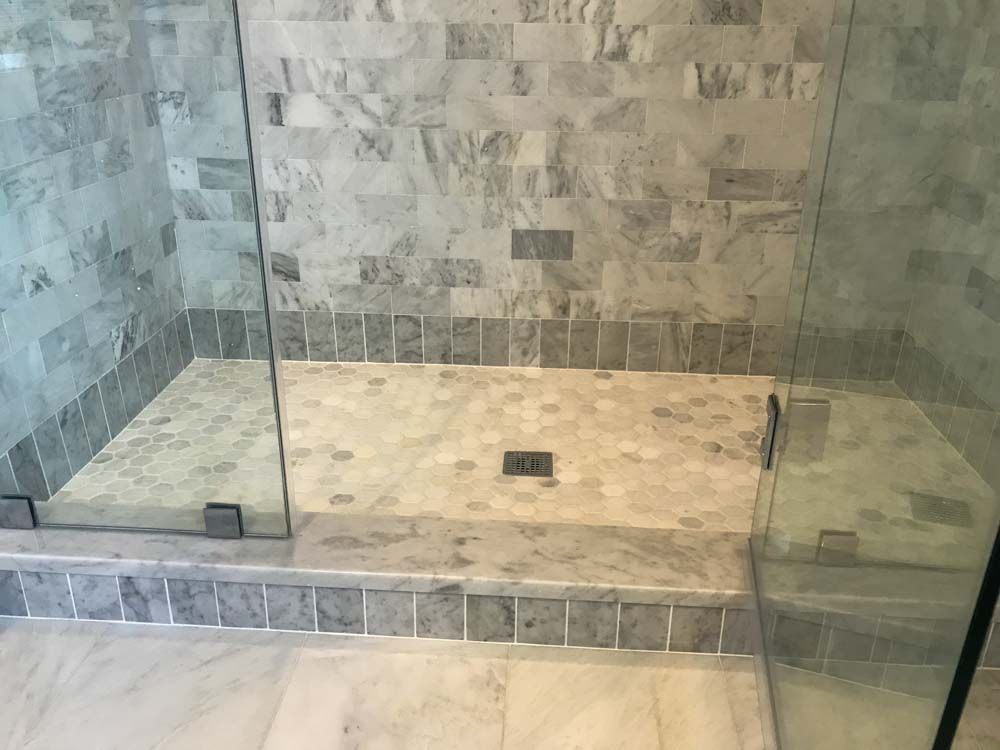 A tiled marble shower with a glass door.