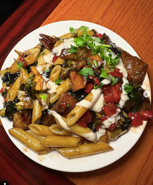 A white plate topped with pasta and vegetables at Mama’s Cafe Baci