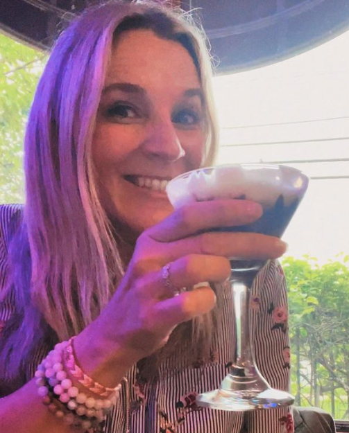 A woman is holding a martini in her hand and smiling at Mama’s Cafe Baci