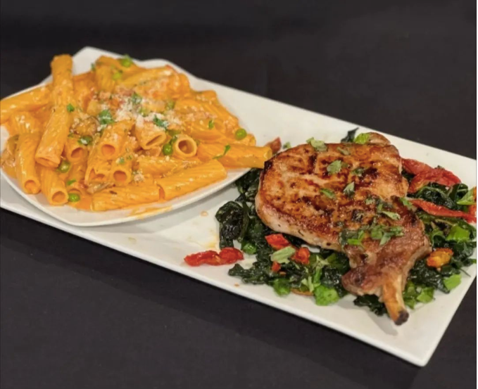 A plate of pasta and a plate of meat on a table at Mama’s Cafe Baci