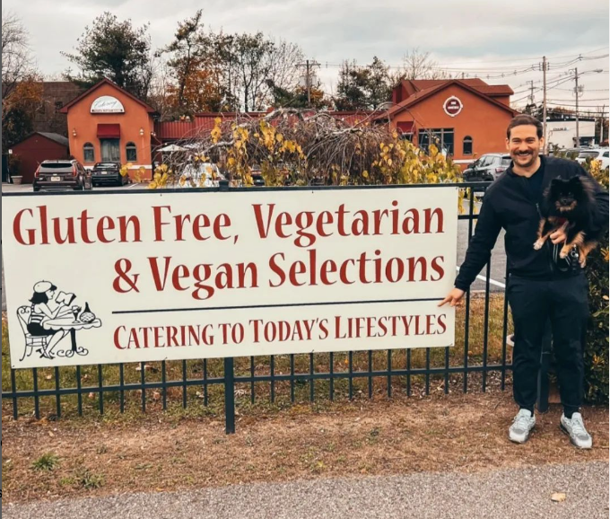 A man standing in front of a sign that says gluten free vegetarian and vegan selections at Mama’s Cafe Baci