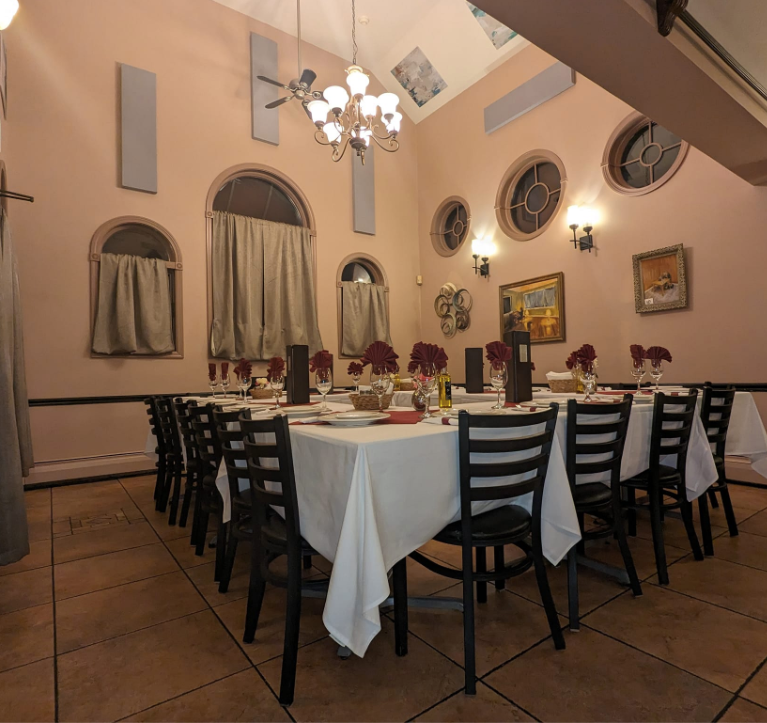 A large room with tables and chairs and a chandelier at Mama’s Cafe Baci