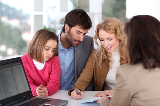 Woman signing paperwork with family beside her