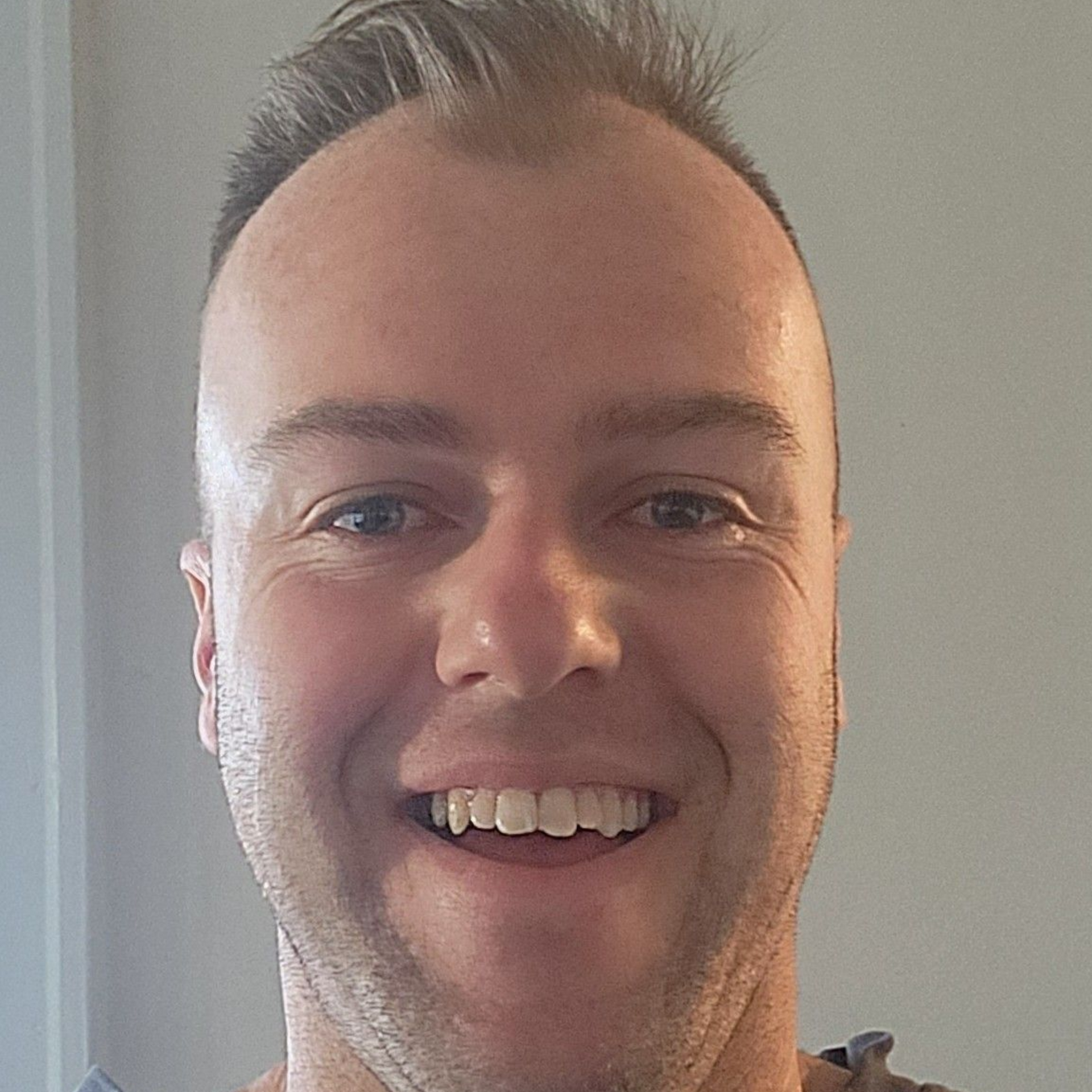 A woman with blonde hair is smiling and praying on the beach.