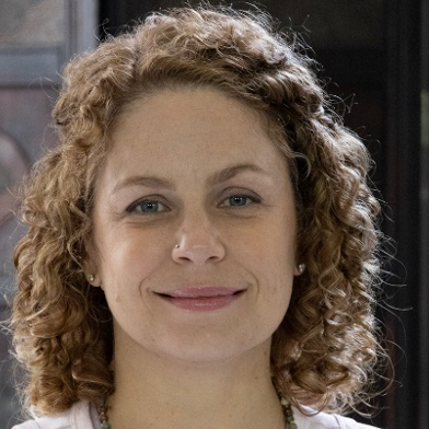 A woman with curly hair is smiling for the camera.