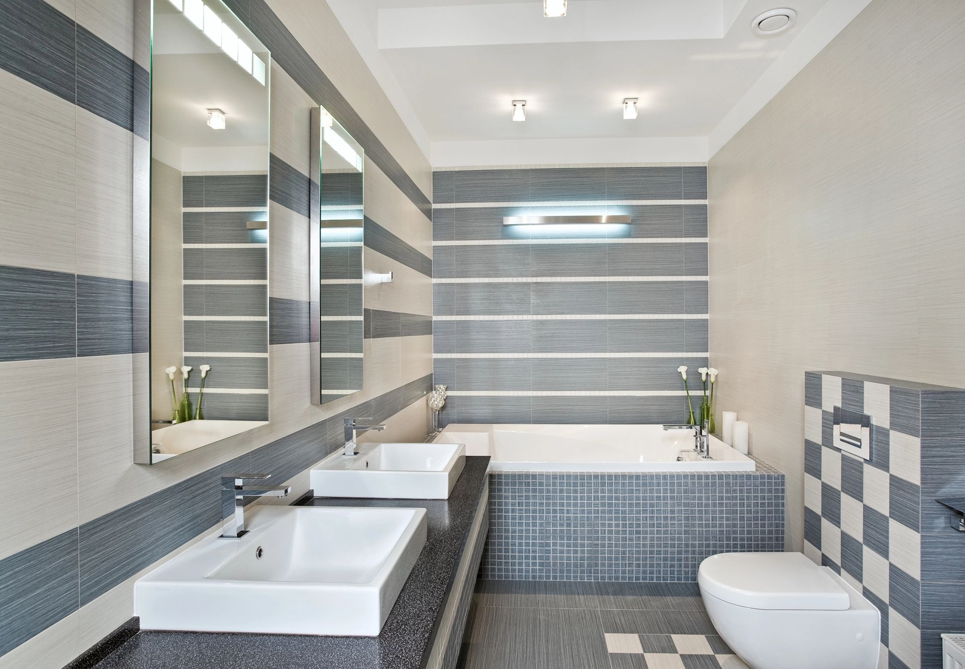Bagno moderno con doppio lavabo, pareti rivestite con piastrelle a righe, vasca da bagno e WC.