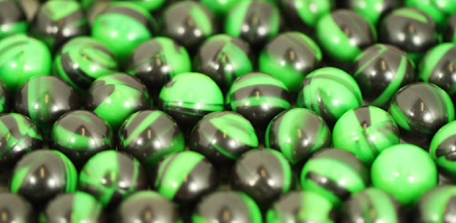 A pile of green and black marbles on a table.