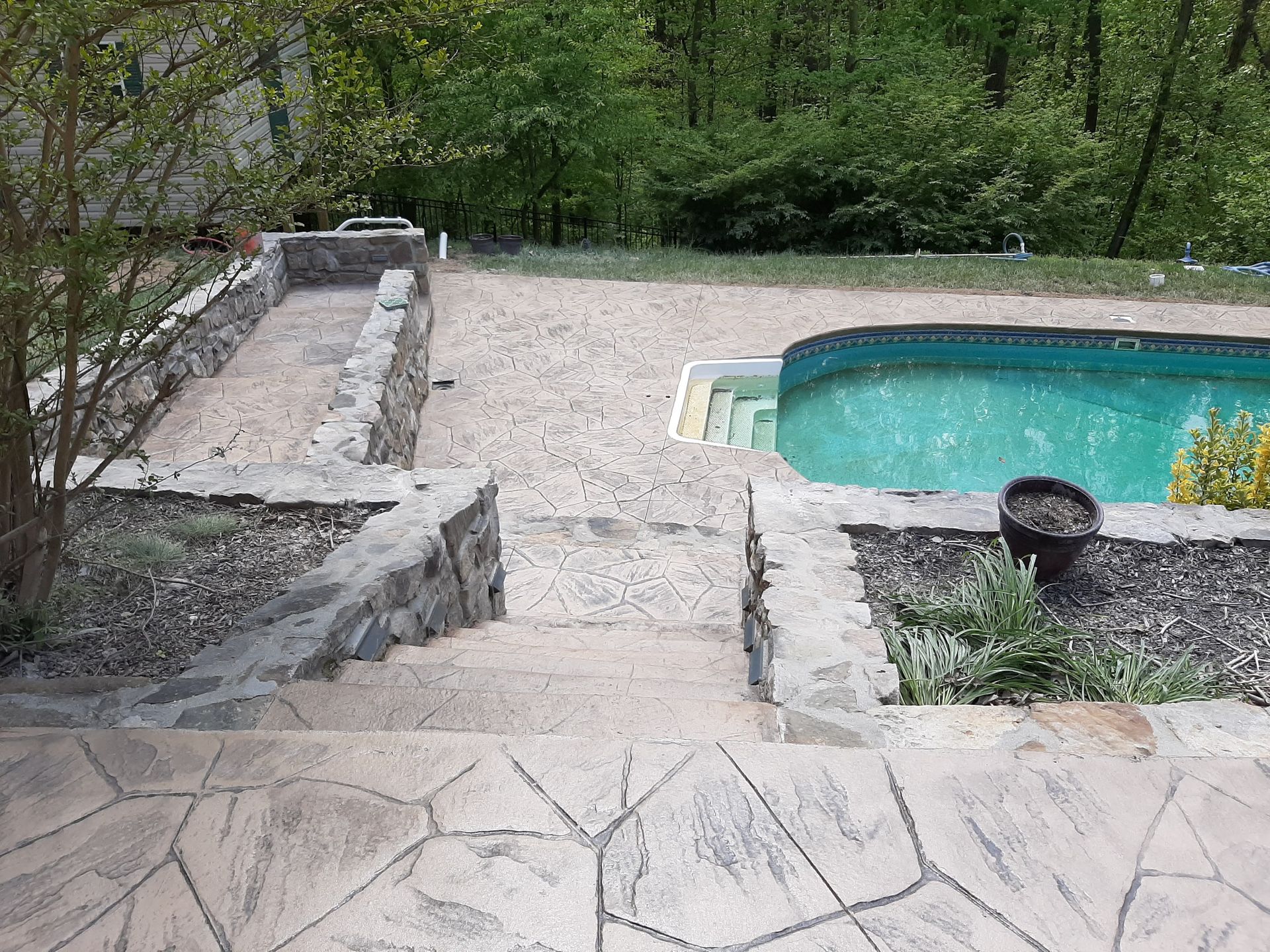 A swimming pool is surrounded by a stone wall and stairs.