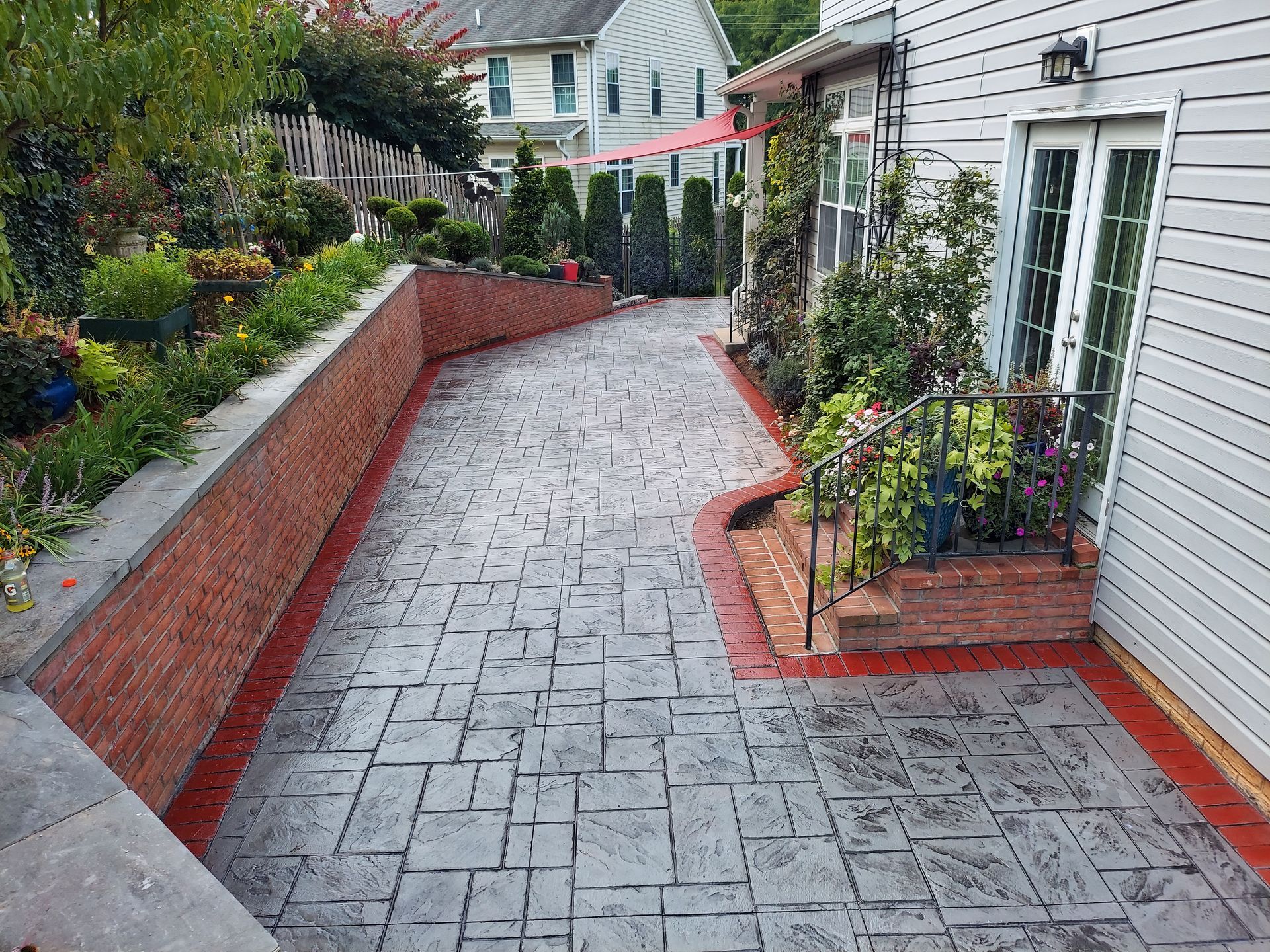A brick walkway leading to a house with a patio in the background.