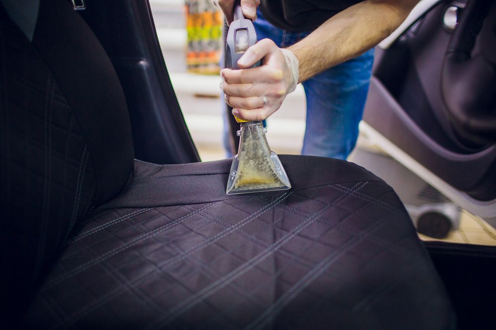 A Man Is Cleaning The Leather Seat Of A Car With A Vacuum Cleaner — Furniture & Auto Pride in Forster, NSW