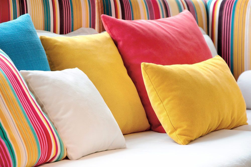 A White Couch With Many Colourful Pillows On It — Furniture & Auto Pride in Port Macquarie, NSW