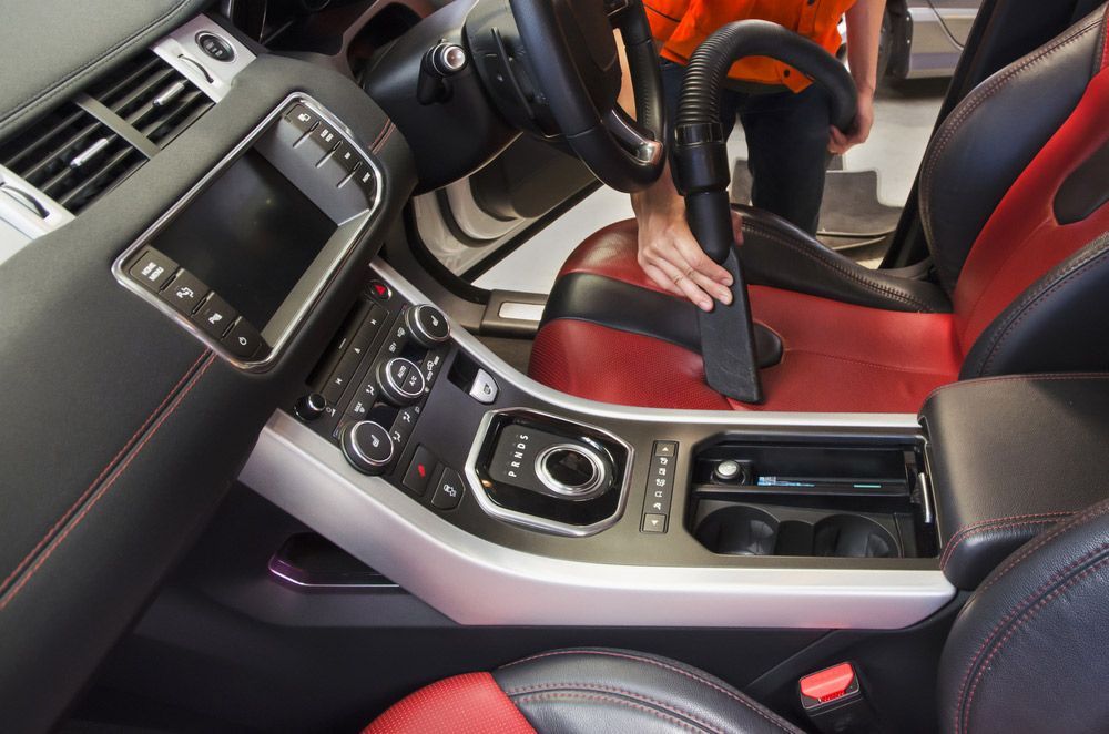 A Person Is Cleaning The Interior Of A Car With A Vacuum Cleaner — Furniture & Auto Pride in South West Rocks, NSW