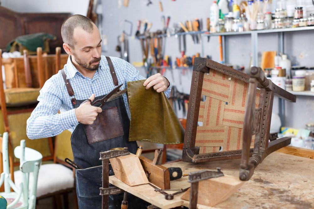 A Man Is Working On A Chair In A Workshop — Furniture & Auto Pride in Bonny Hills, NSW