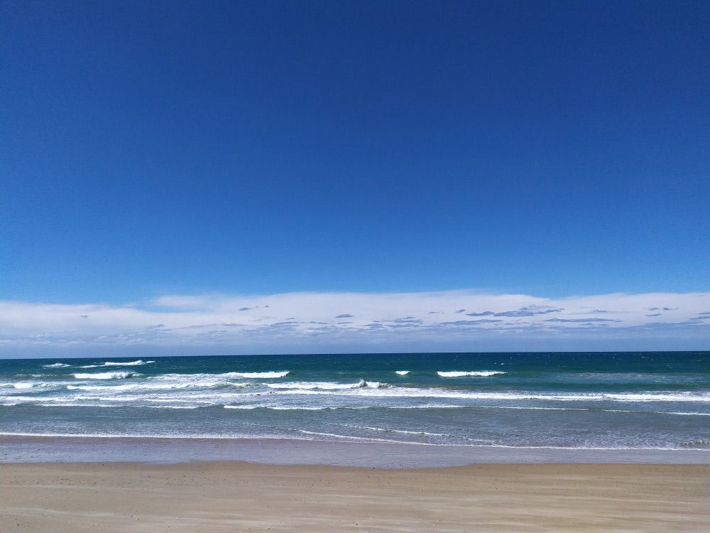 A Beach With A Blue Sky And Waves Coming In — Furniture & Auto Pride in Old Bar, NSW