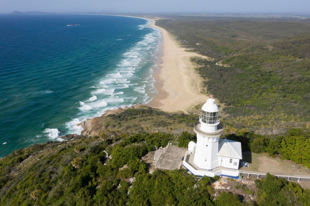 An Aerial View Of A Lighthouse On Top Of A Hill Next To A Beach — Furniture & Auto Pride in South West Rocks, NSW
