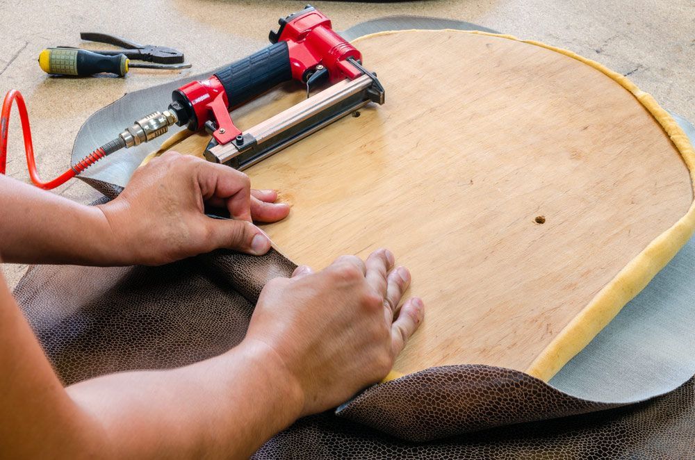 A Person Is Using A Stapler On A Piece Of Wood — Furniture & Auto Pride in Harrington, NSW