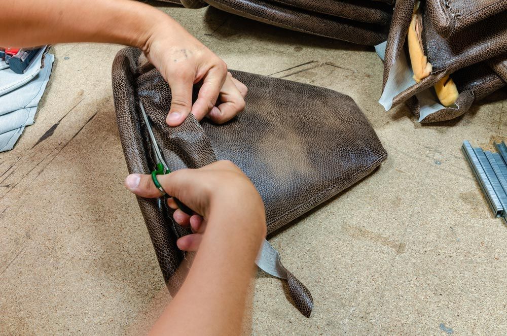 A Person Is Cutting A Piece Of Leather With Scissors — Furniture & Auto Pride in Harrington, NSW