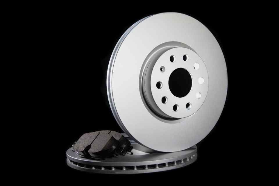 A car is being repaired in a garage with a tire on the ground.