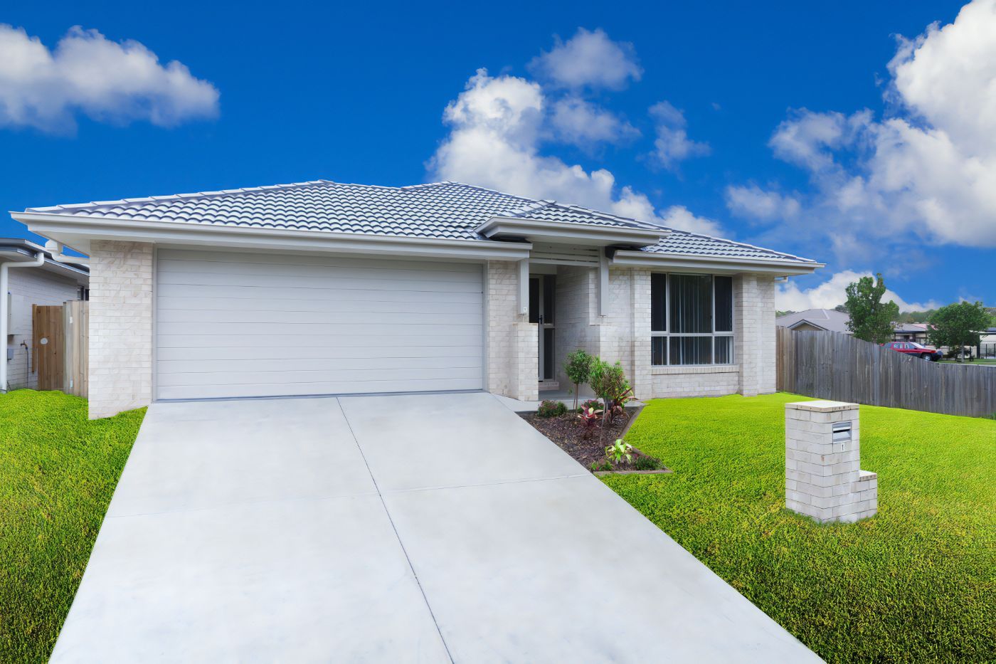 A White House with A White Garage Door and A Concrete Driveway — Cemak Constructions in Lake Cathie, NSW
