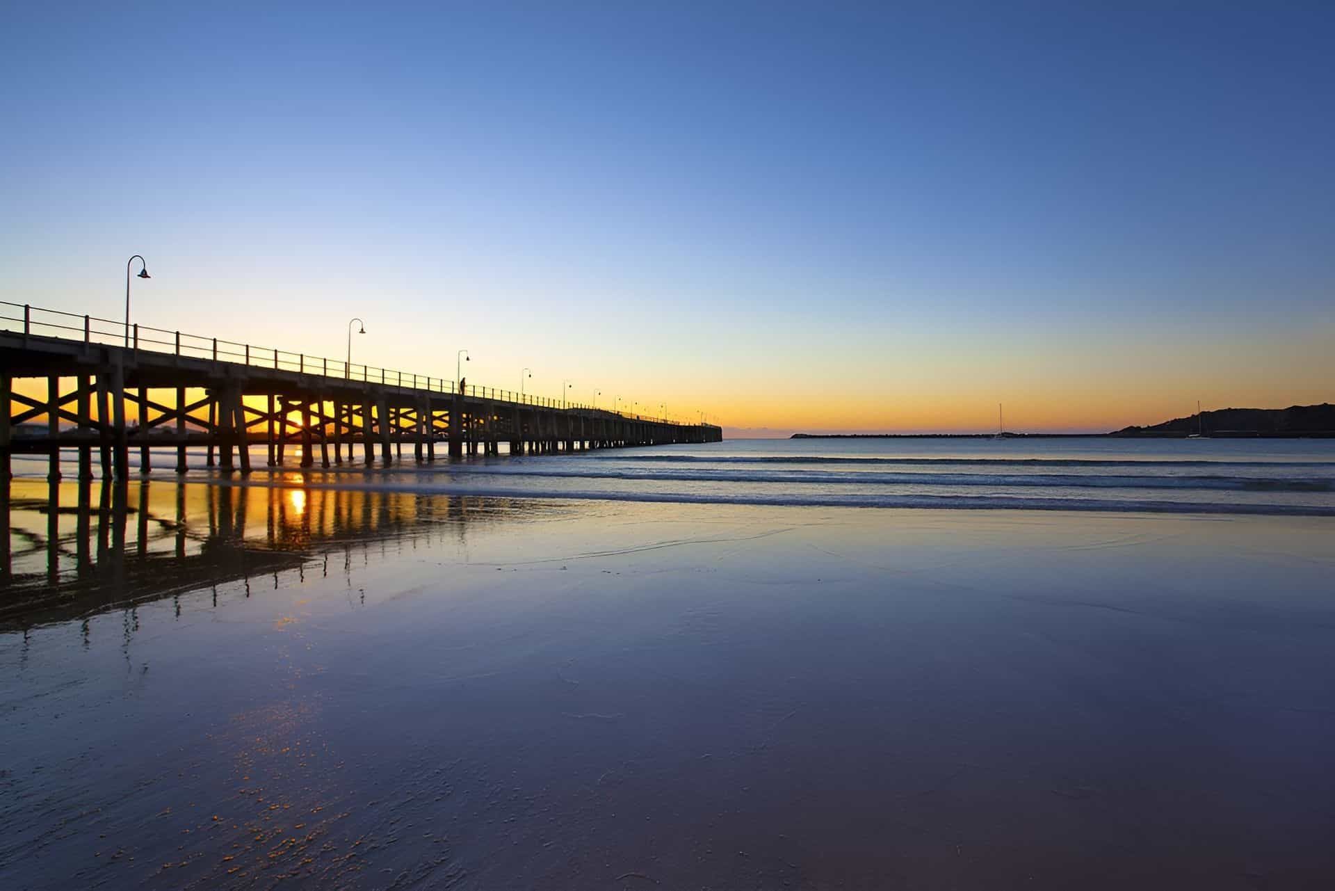 A Pier Overlooking a Body of Water at Sunset — Cemak Constructions in Coffs Harbour, NSW