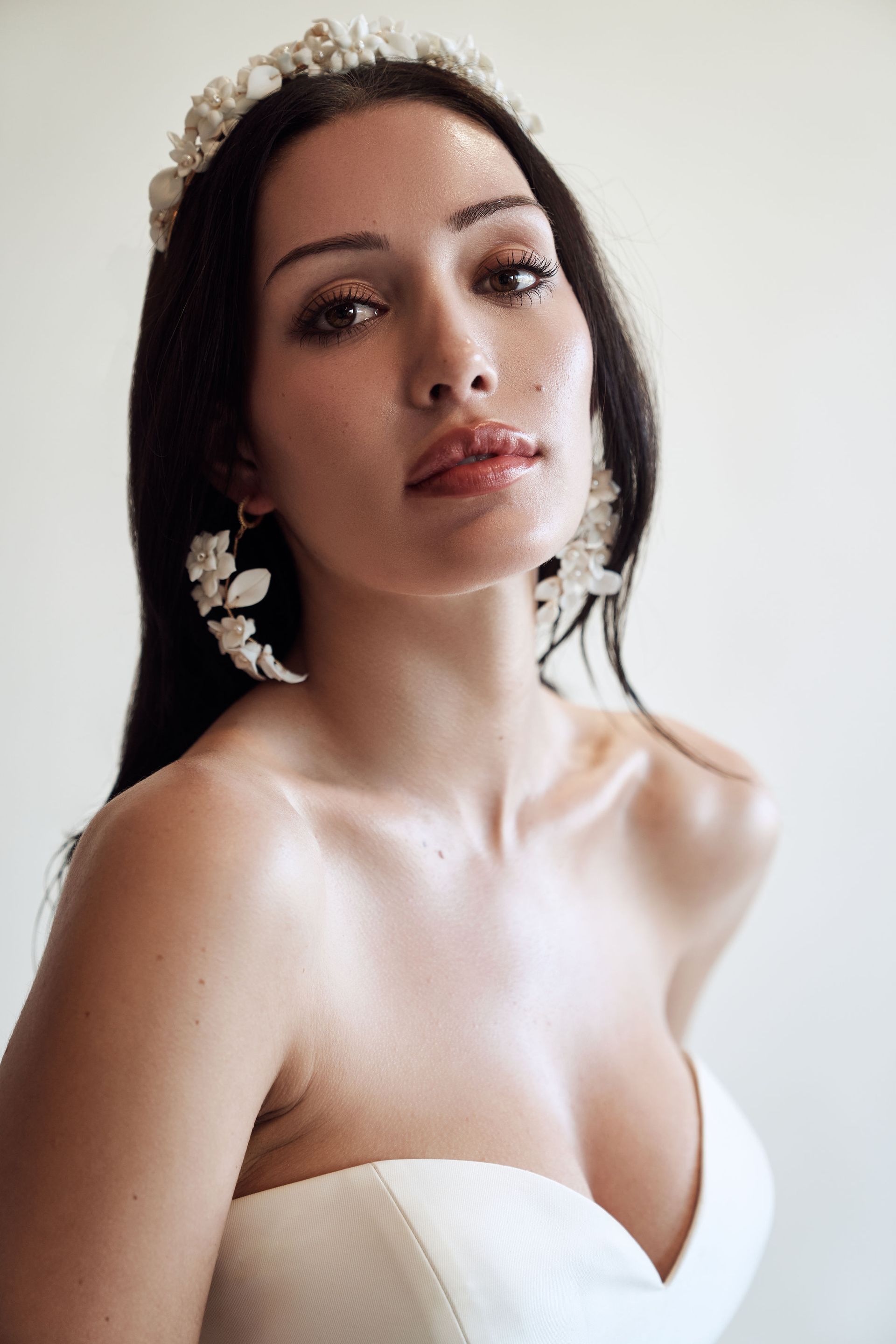 A woman in a wedding dress is wearing a tiara and earrings.