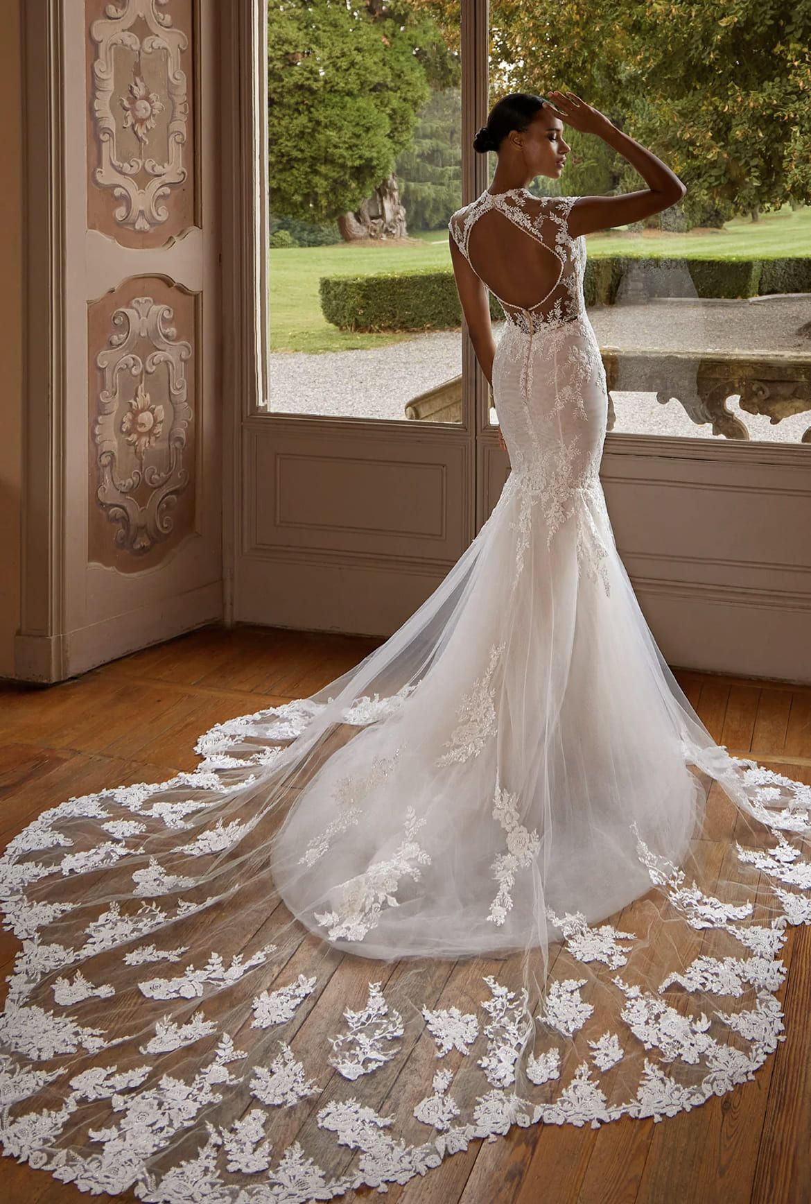 A woman in a wedding dress is standing in front of a window.