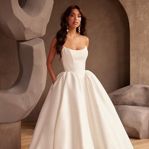 A woman in a wedding dress is standing in front of a mirror in a room.