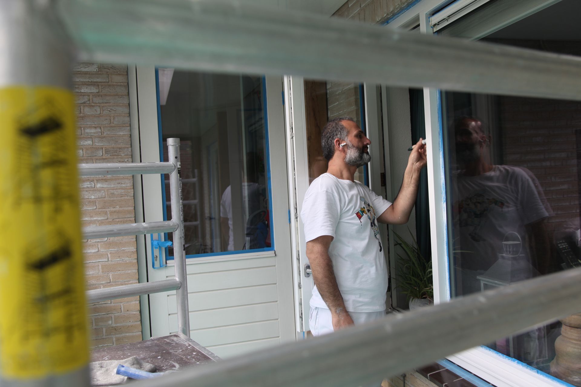 Iemand gebruikt een verfroller om witte verf aan te brengen op een gladde binnenmuur in een woonkamer.
