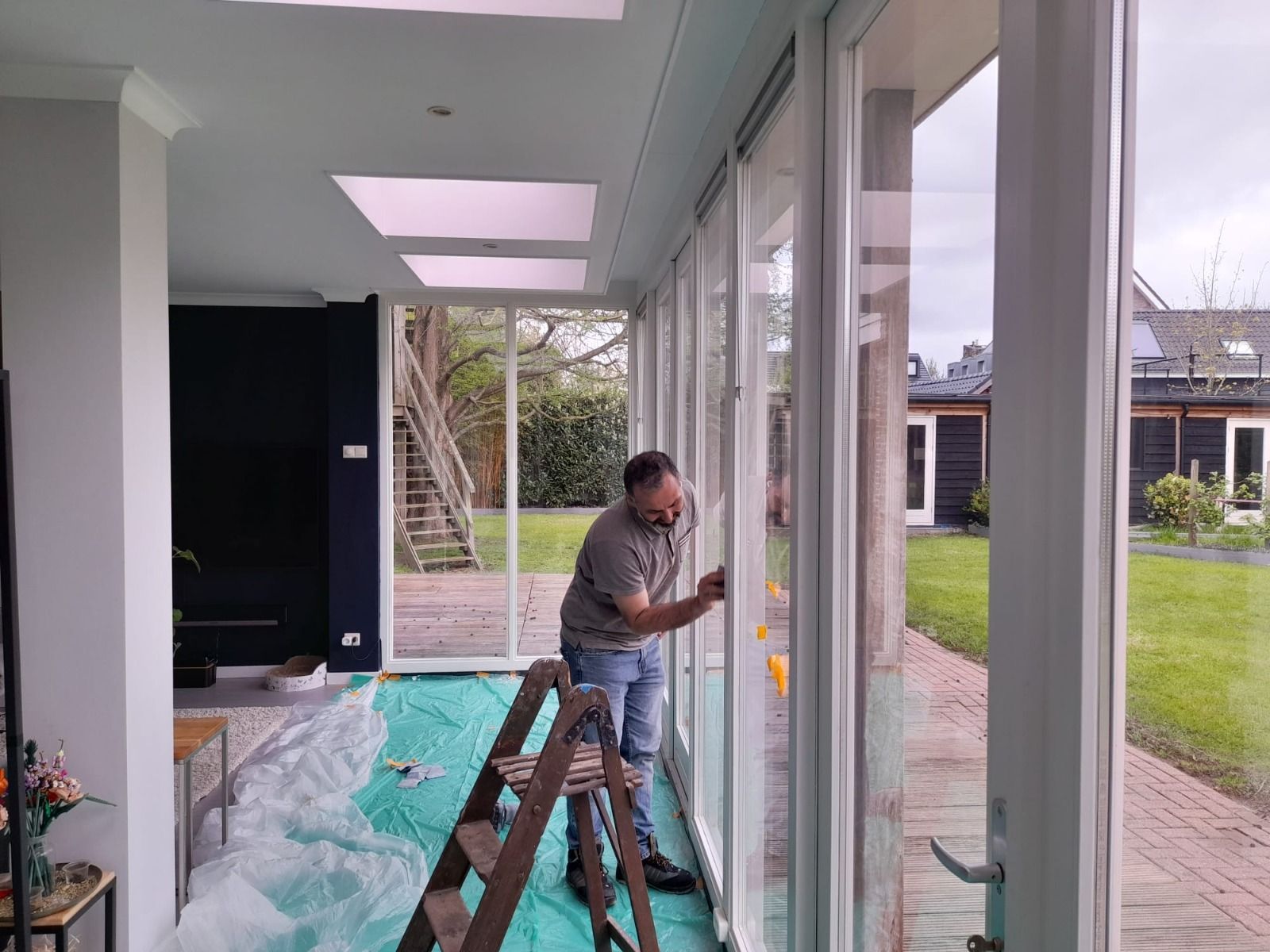 in een lichtblauw shirt raakt een gladde, witte buitenmuur van een huis aan