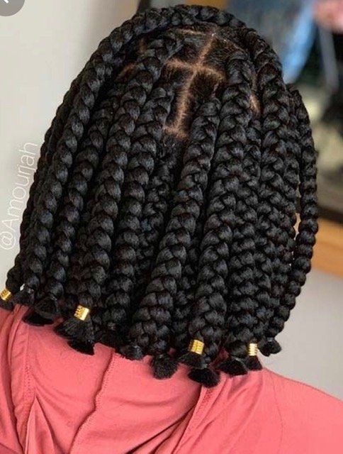 A woman with braids in her hair is wearing a pink shirt.