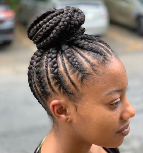 A woman with braids in a bun is smiling.