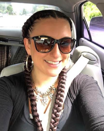 A woman wearing sunglasses and braids is sitting in a car
