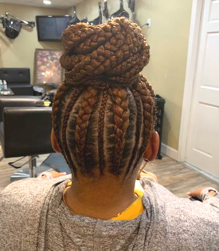 A woman with braids in a bun is sitting in a salon.