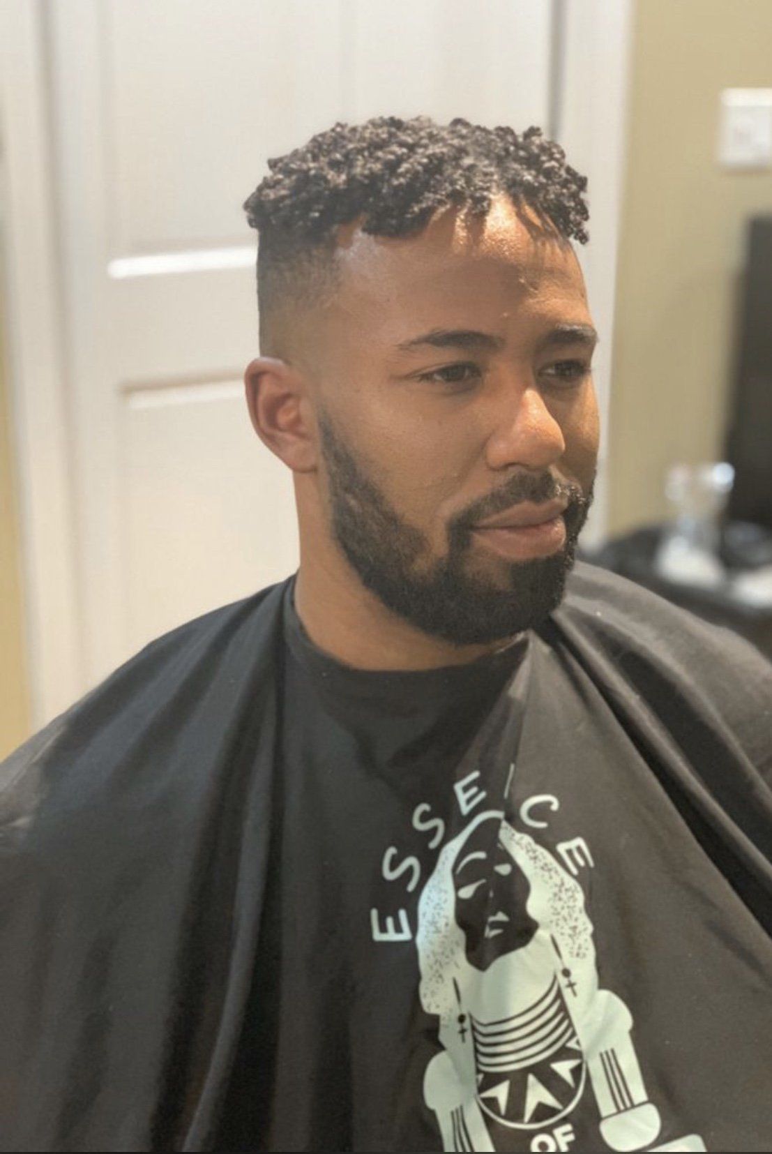 A man with a beard is getting his hair cut by a barber.