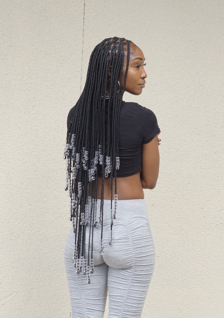 A woman with braids is wearing a black crop top and grey pants