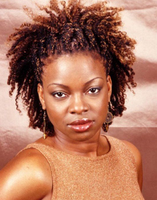 A woman with curly hair is wearing a gold tank top