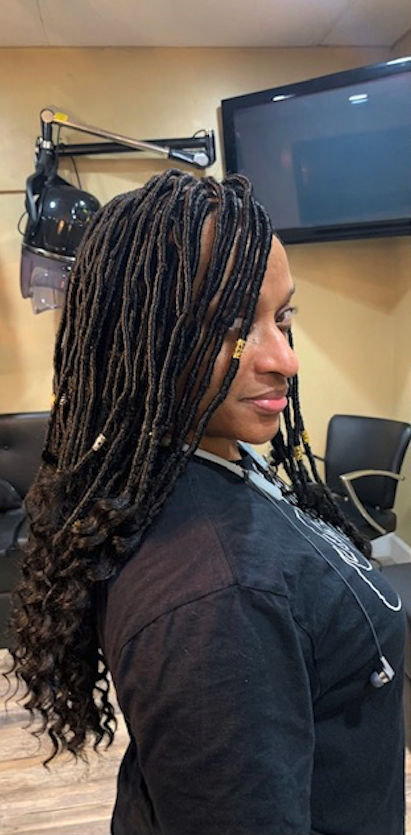 A woman with braids in her hair is standing in a salon.