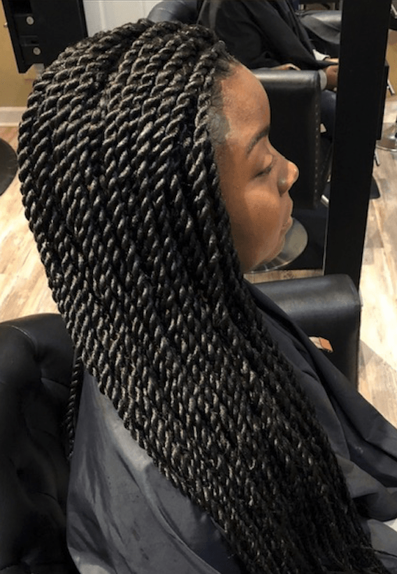 A woman with braids is sitting in a chair in a salon.