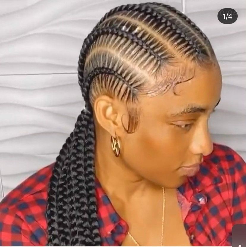A woman wearing a plaid shirt and earrings has braids in her hair.