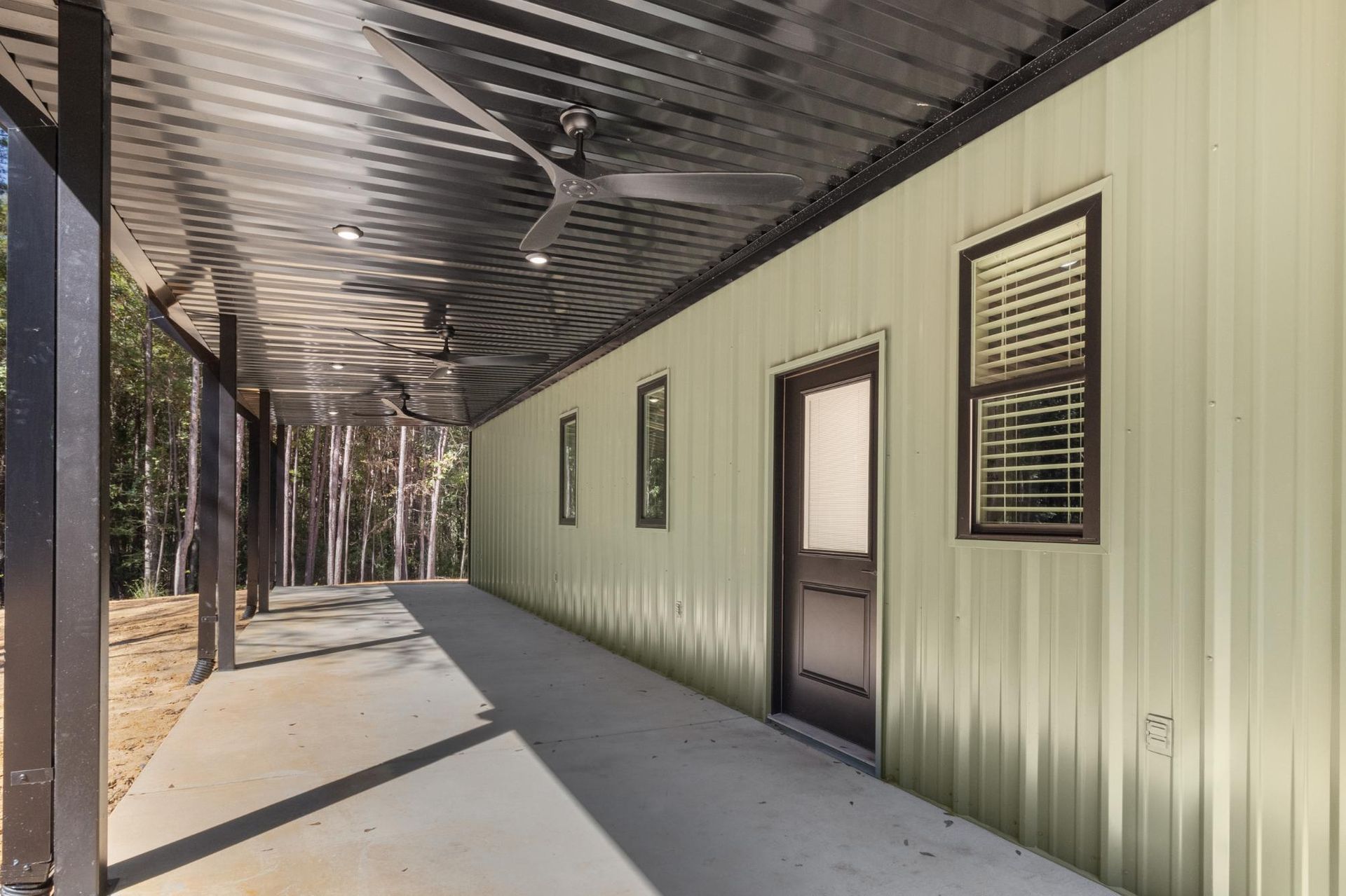 Covered porch with a corrugated metal roof and a light green metal-sided building.