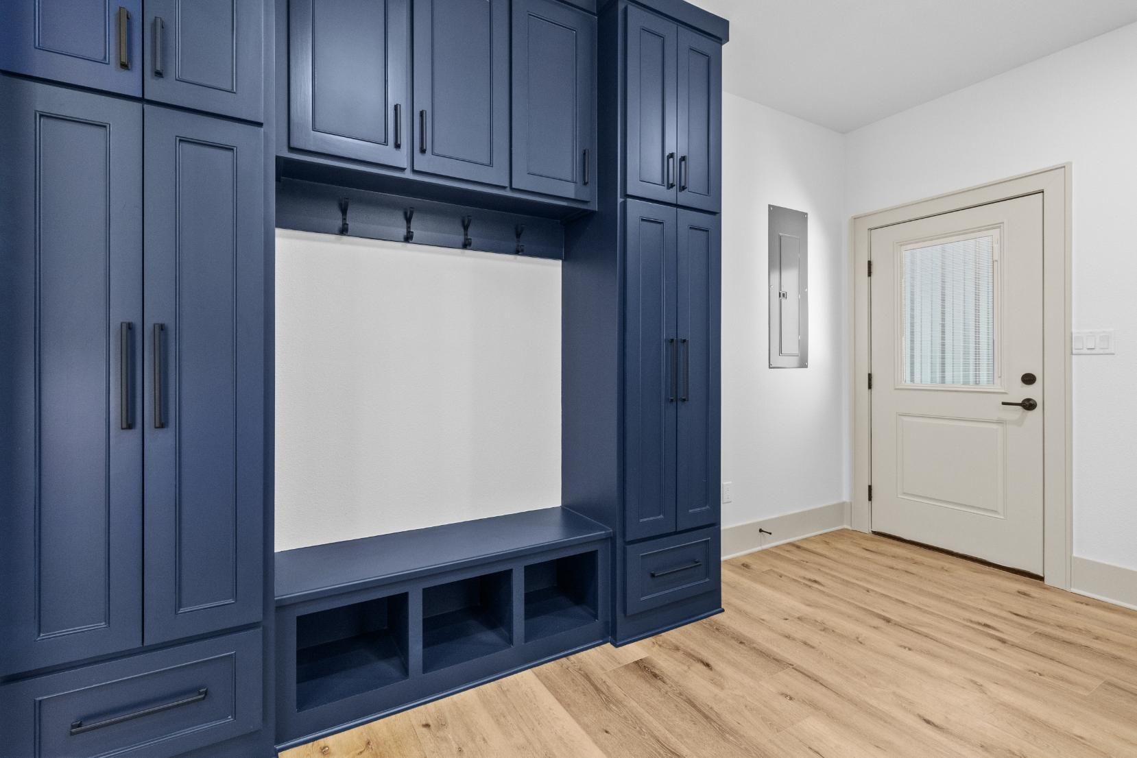 Blue built-in storage unit in a room with white walls, a door, and wood-look flooring.