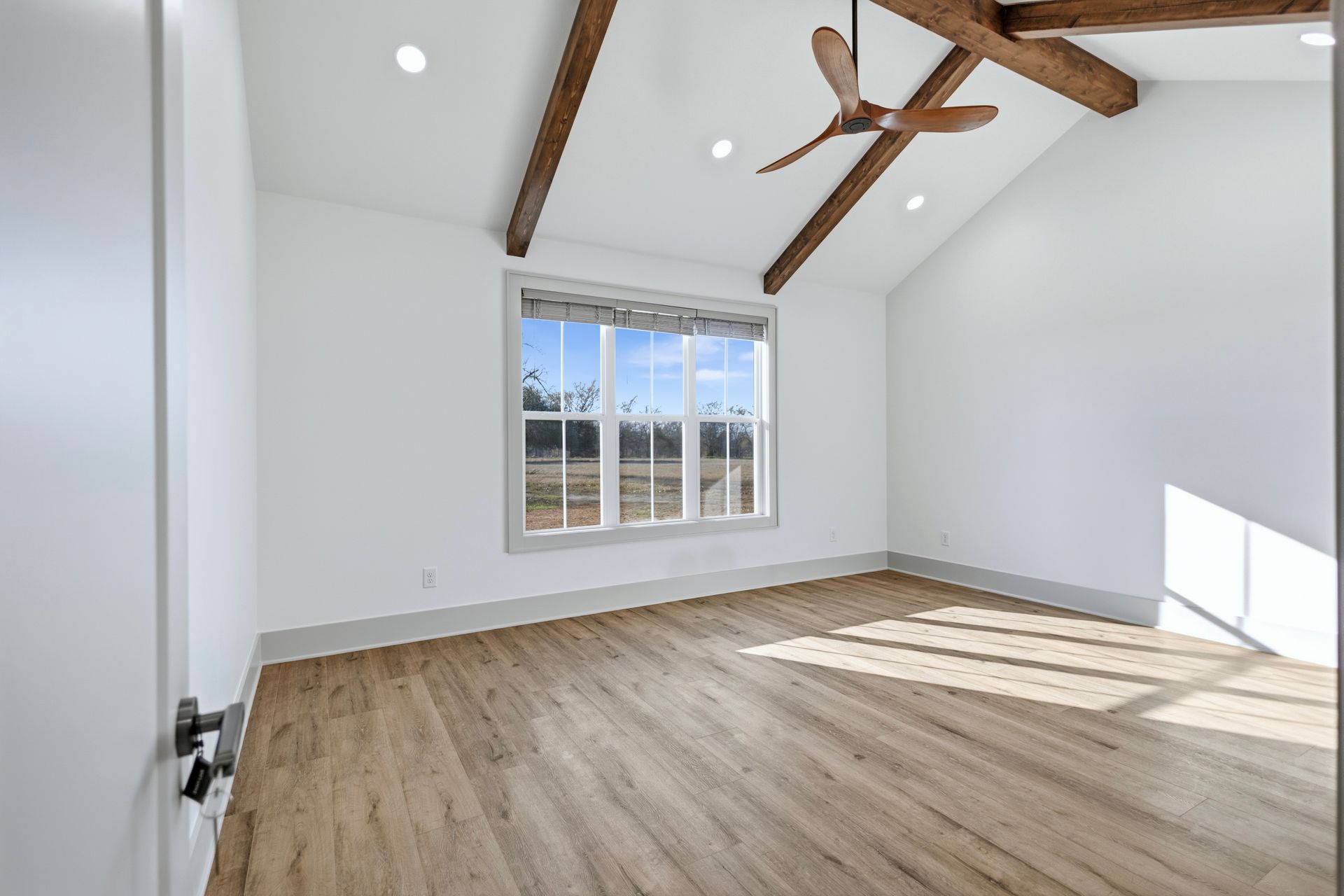 Empty metal warehouse interior with high ceilings, large fan, and concrete floor.
