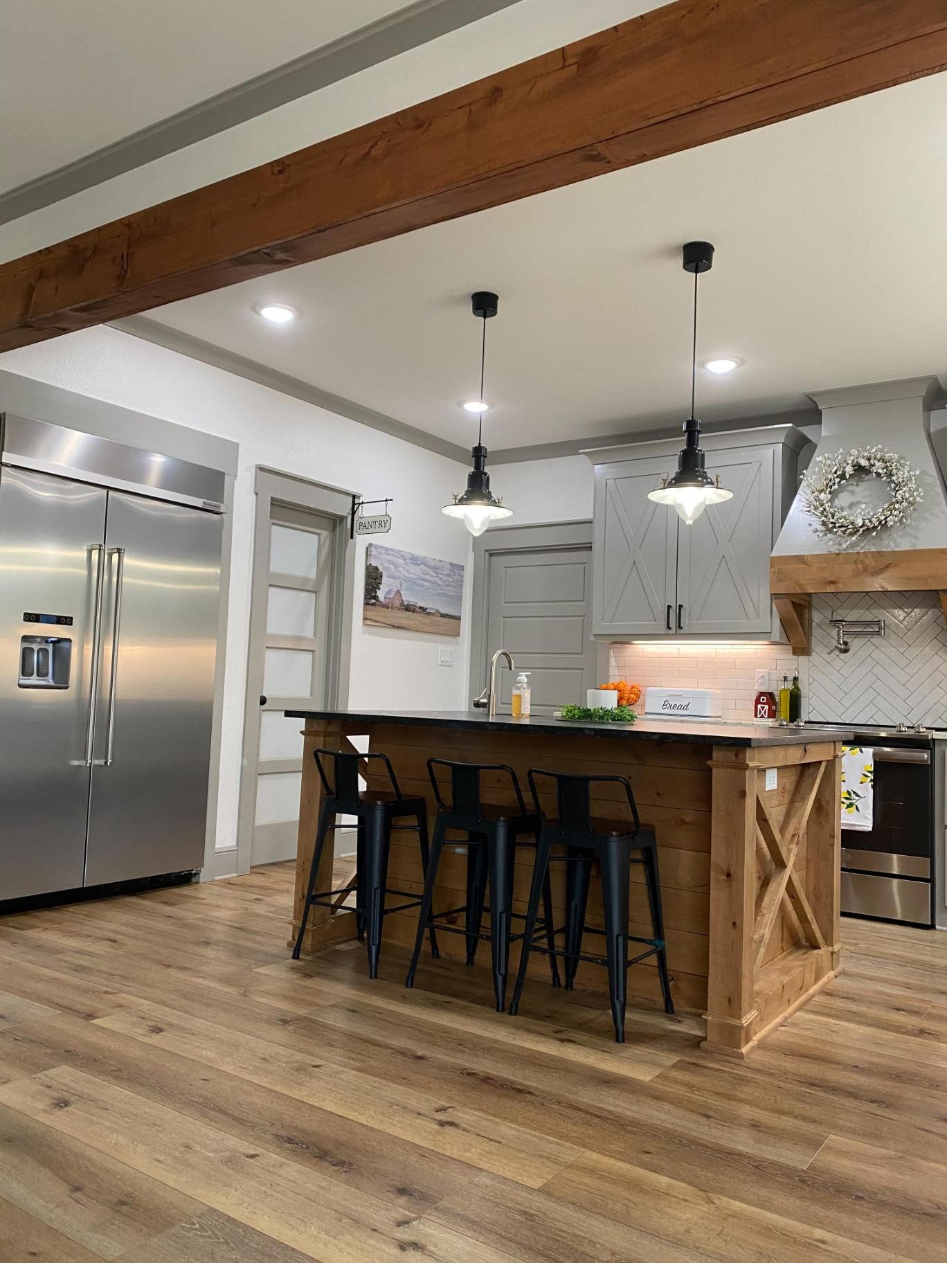 Spacious kitchen with wood floors, an island with bar stools, and stainless steel appliances.