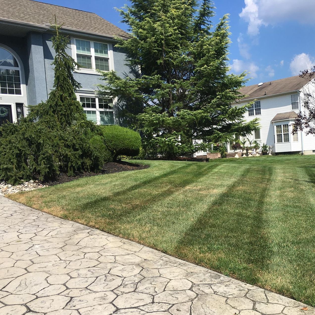 A large house with a freshly mowed, lush green lawn in front of it.