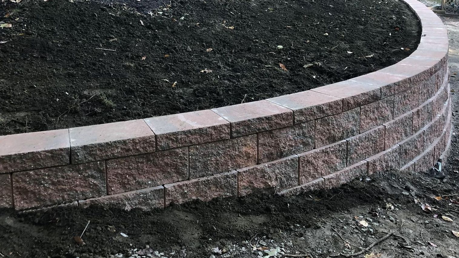 A wooden fence surrounds a concrete driveway in front of outdoor entertainment area.