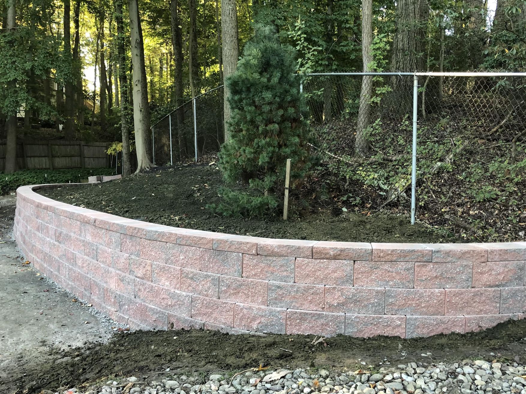 A block retaining wall is being built in the a homeowner's backyard.