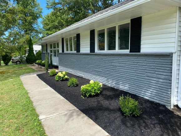 A white house with a black roof and black mulch in front of it